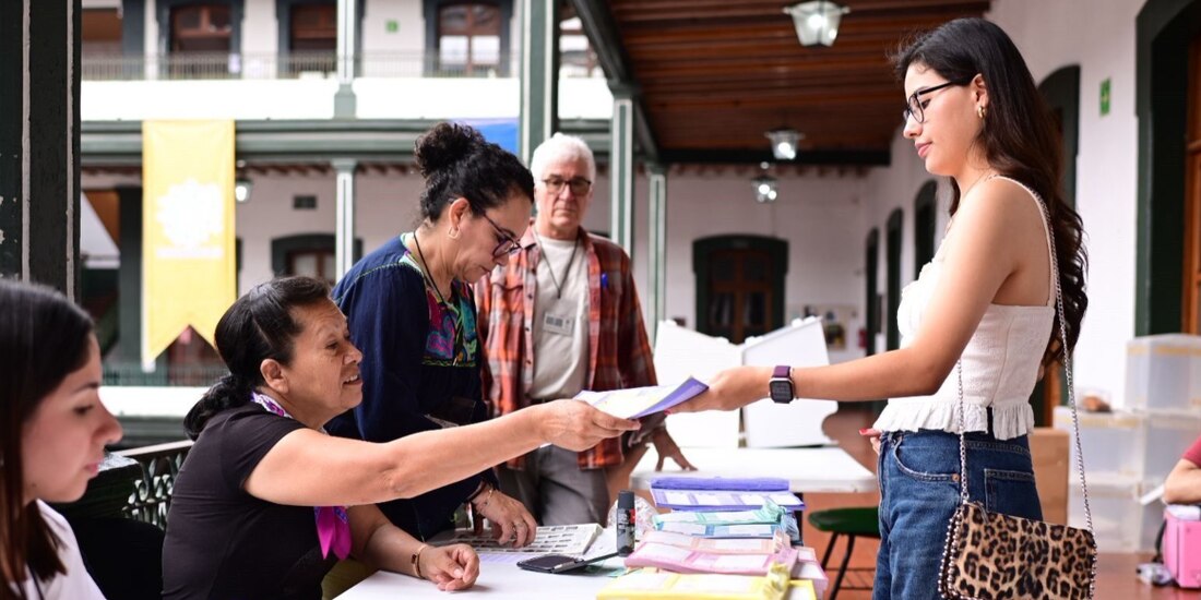 Una funcionaria de casilla entrega a una joven su paquete de boletas para ejercer su voto en el puerto de Veracruz, ayer.