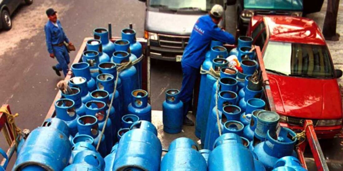 Un camión cargado con varios cilindros azules de gas en una jornada de trabajo.