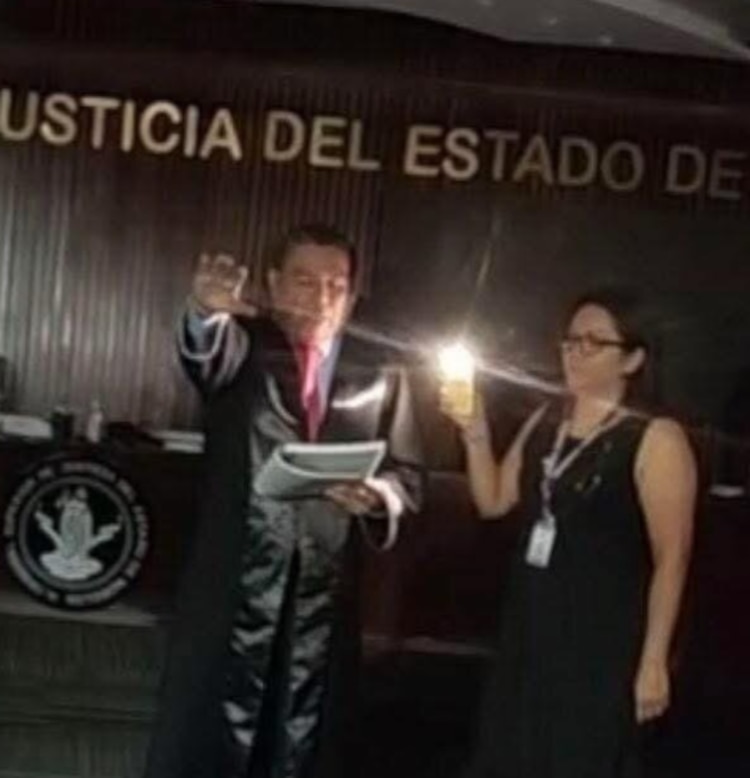 El magistrado Juan Gabriel Vargas Téllez, al rendir protesta como nuevo presidente del Tribunal Superior de Justicia, alumbrado por una lámpara de celular.
