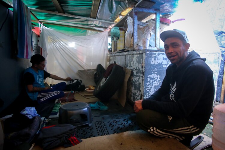 Darío (der.) come en una cocina improvisada que construyó.
