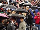 Asistentes, ayer, cubriéndose de la lluvia en el Zócalo.