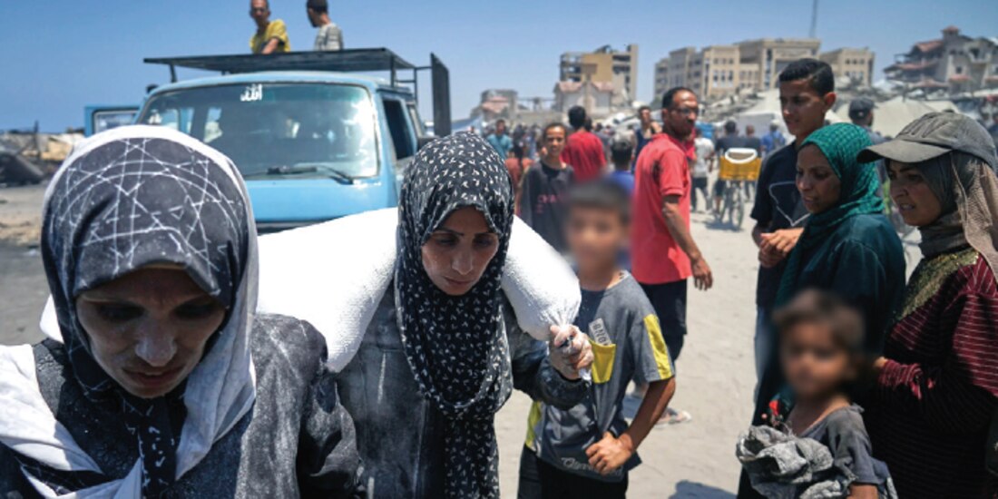 Iman Shabat, madre de cinco hijos, lleva un saco de harina descargado de un convoy de ayuda humanitaria, el pasado 22 de julio.