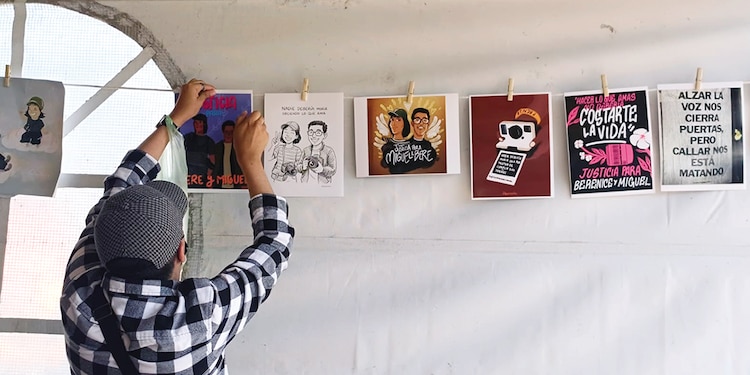 Una persona coloca en un tendedero hojas con consignas e ilustraciones para exigir justicia para los dos jóvenes.
