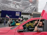 UN HOMBRE hace el signo de la victoria mientras porta una bandera iraní, el 13 de abril