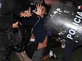 Jóvenes se protegen ante la agresión de policías durante las protestas del pasado lunes en Cancún.