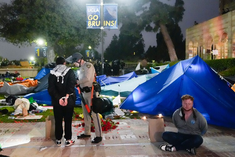 Un oficial arresta a presuntos alumnos que rechazaron el desalojo.