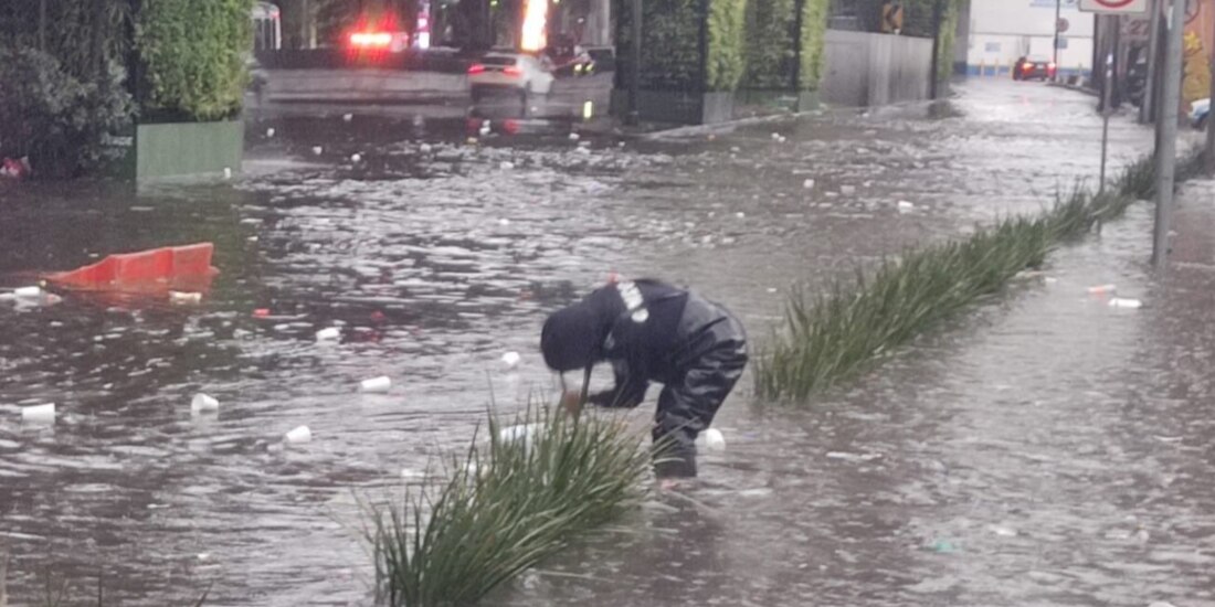 Un oficial trabaja en el destape de una coladera ayer, en medio de un enchacamiento con restos de basura.