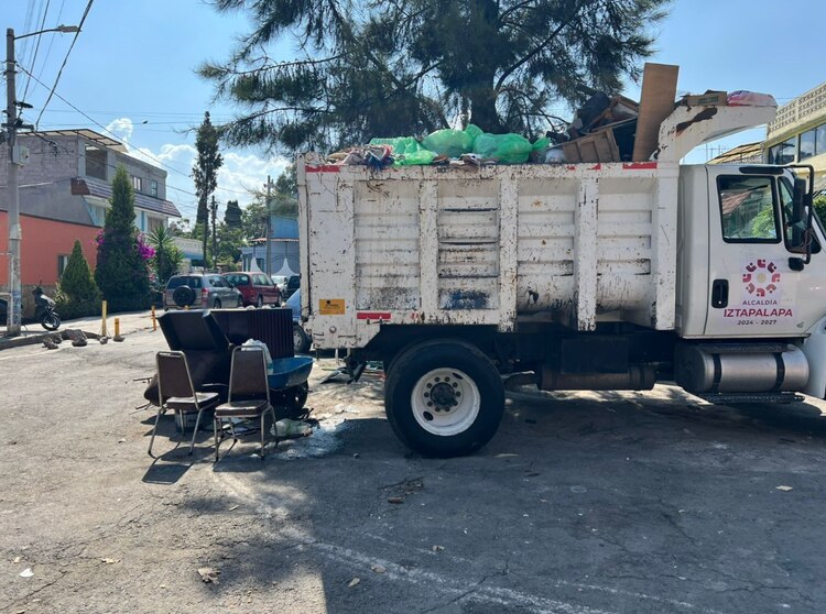 Un camión recolector de basura carga con muebles echados a perder, ayer.