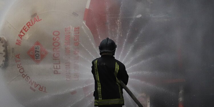 Un bombero de la capital intenta enfriar el contenedor de la pipa de gas que se volcó la tarde del miércoles en Iztapalapa.