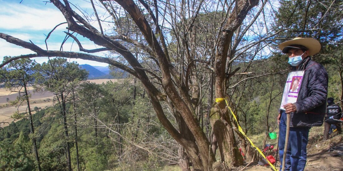 Un hombre, quien porta la imegn de una persona desaparecida, observa a activistas durante las acciones de búsqueda de restos en una zona del Ajusco, el 29 de abril.