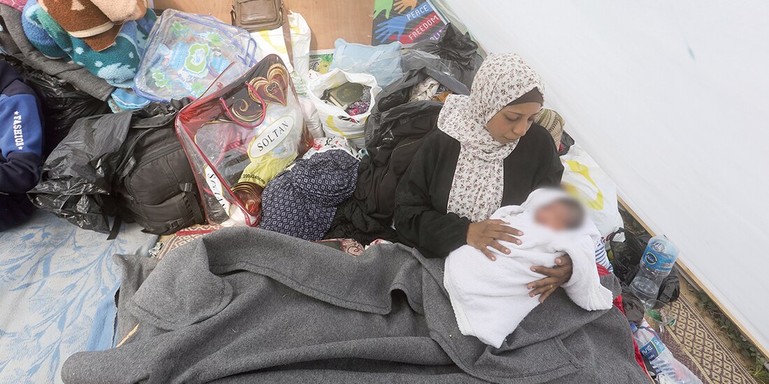 Una mujer palestina desplazada sostiene a su bebé en una tienda de campaña cerca del cruce de Kerem Shalom en Rafah el pasado 14 de enero.