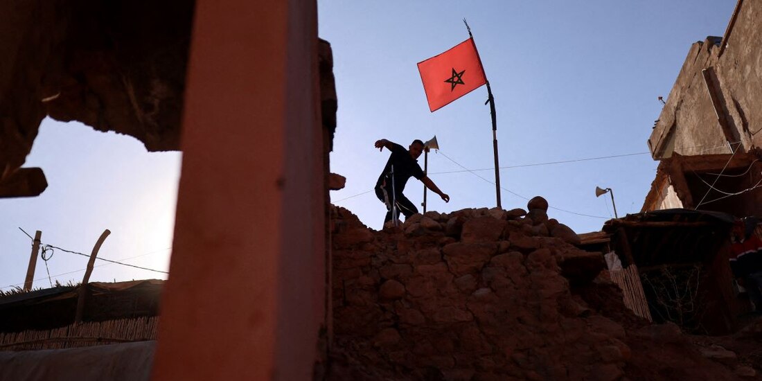 Un hombre camina entre los escombros, junto a una bandera marroquí, tras un terremoto mortal en el pueblo de Talat N'Yaaqoub, Marruecos.