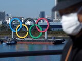 Un hombre con cubrebocas pasa frente a los anillos olímpicos en Tokio el e de diciembre de 2020. Un rebrote del coronavirus hace que surjan dudas acerca de la realización de los Juegos Olímpicos a mediados de este año.