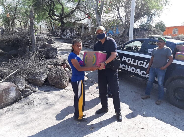 Policía local entrega una caja con alimentos a una madre en situación vulnerable.