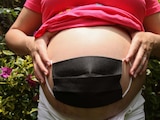 Mujer embarazada se coloca cubrebocas en el vientre como signo de protección para el bebé.