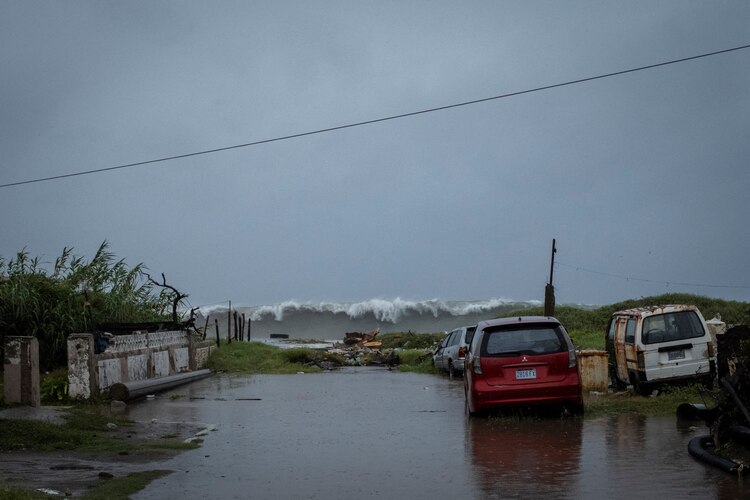 Autos arrastrados por las inundaciones se observan cerca de playas ante un fuerte oleaje de fondo.