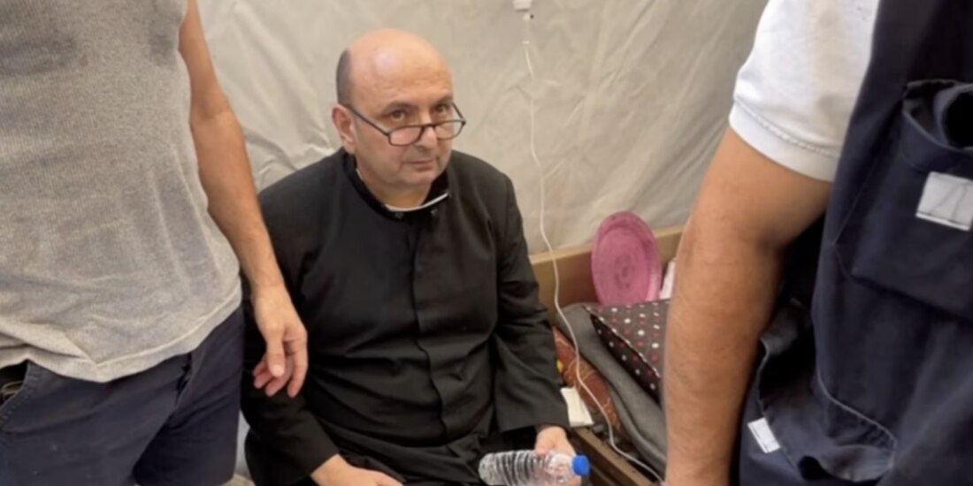 El párroco de la Iglesia de la Sagrada Familia, el padre Gabriele Romanelli, recibe atención médica tras un ataque israelí contra iglesia, ayer.