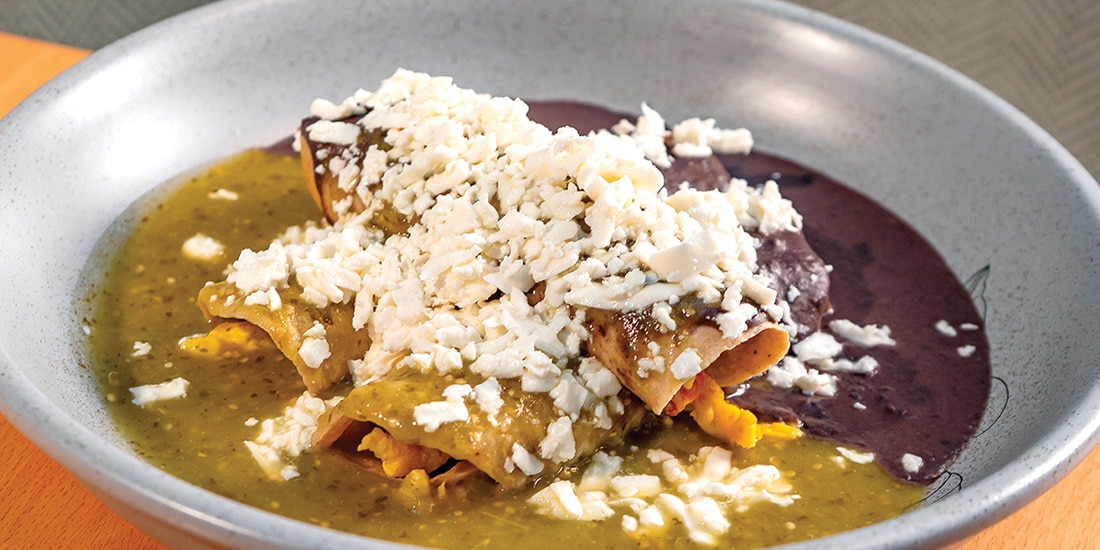 Huevos Dueto. Tres tacos de huevo a la mexicana cubiertos con caldo de frijol negro, salsa verde y queso fresco.