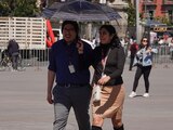 Una pareja se cubren de los intensos rayos del sol en el Zócalo capitalino