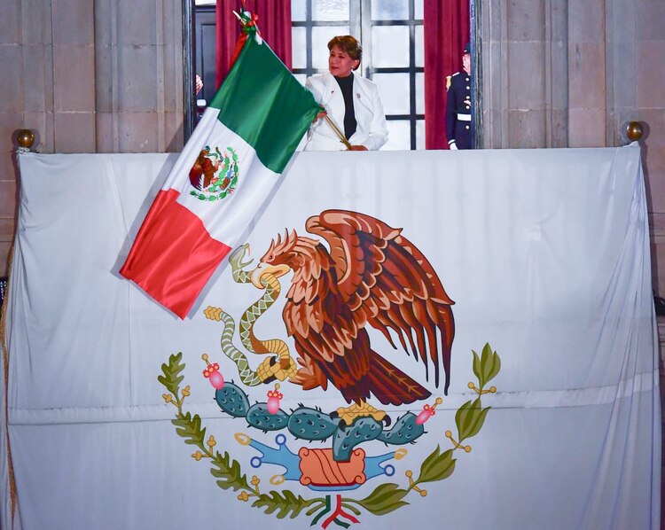 La Gobernadora Delfina Gómez Álvarez ondea la bandera nacional desde el balcón del Palacio de Gobierno en Toluca.