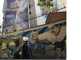 Un clérigo iraní camina junto a una valla publicitaria antiisraelí en un edificio en Teherán, antes de los ataques de EU, ayer.