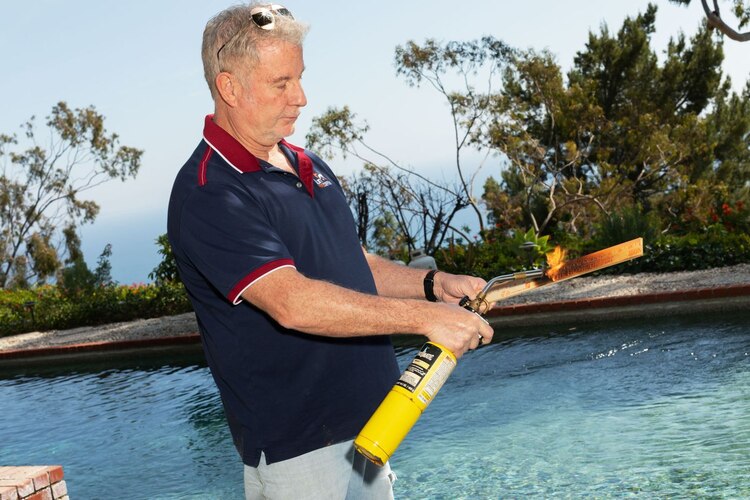 Jim Moseley usa un soplete de mano para demostrar SPF 3000 en una pieza de madera en Malibu, California.