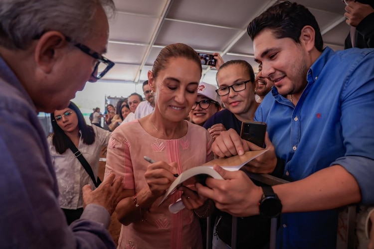 Presidenta Claudia Sheinbaum firma un libro durante su gira de trabajo en Sinaloa.