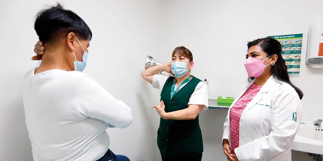 Una enfermera explica a una mujer cómo hacerse una revisión de seno para detectar tumores cancerígenos.