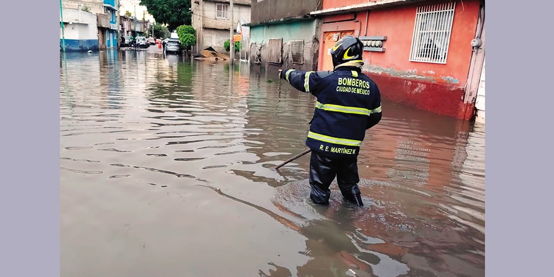 UN BOMBERO atiende ayer una inundación en Iztapalapa tras una fuerte tromba.