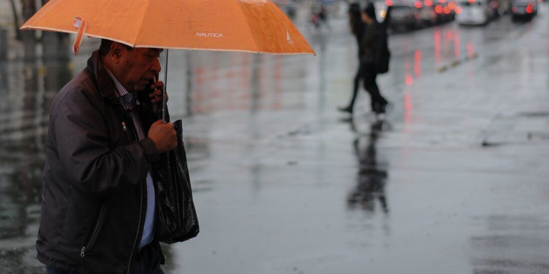 Un capitalino se resguarda de las fuertes lluvias en calles de la CDMX.