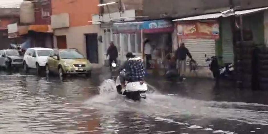 Una persona en motoneta sortea un charco en Nezahualcóyotl, Edomex