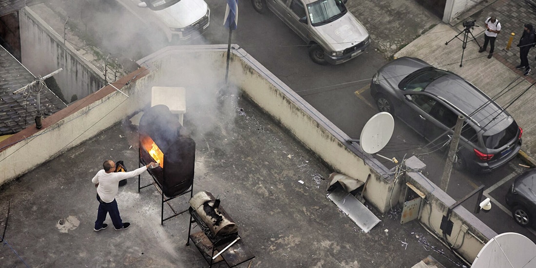 Un hombre quema papeles supuestamente en el techo de la embajada de Cuba en Quito, ayer.