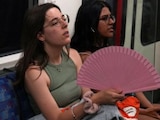 Una mujer se refresca con un abanico al interior de un vagón del metro de Londres.