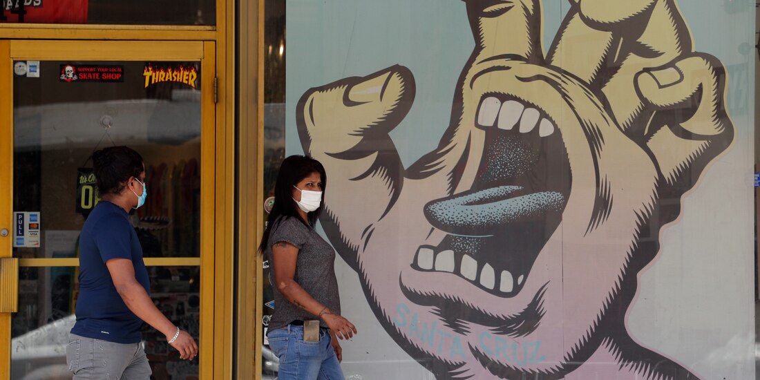 Personas usan cubrebocas para protegerse del COVID-19, pasan por un negocio que ha reabierto, en San Antonio, el 24 de junio de 2020.