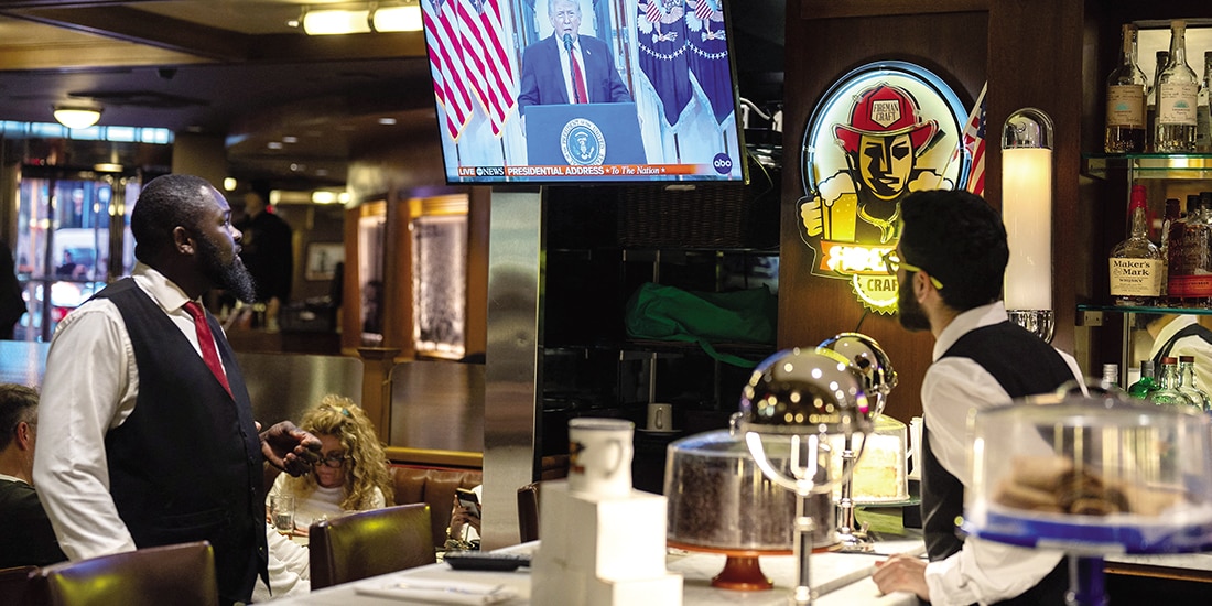 TRABAJADORES observan el discurso de Trump, ayer.