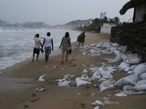 Un grupo de personas camina sobre una playa de Acapulco, horas antes de la llegada del huracán 'Otis'.