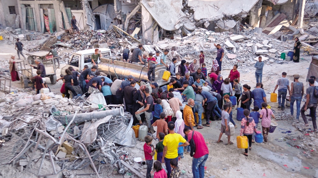 Palestinos recogen agua de un camión en medio de la destrucción causada por la ofensiva aérea y terrestre israelí, en la ciudad de Gaza, el 16 de octubre.