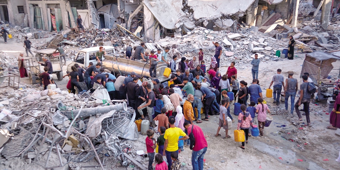 Palestinos recogen agua de un camión en medio de la destrucción causada por la ofensiva aérea y terrestre israelí, en la ciudad de Gaza, el 16 de octubre.