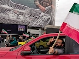 Un hombre porta una bandera iraní en Teherán.