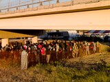 Migrantes hacen fila para subir a los autobuses en Texas, ayer.