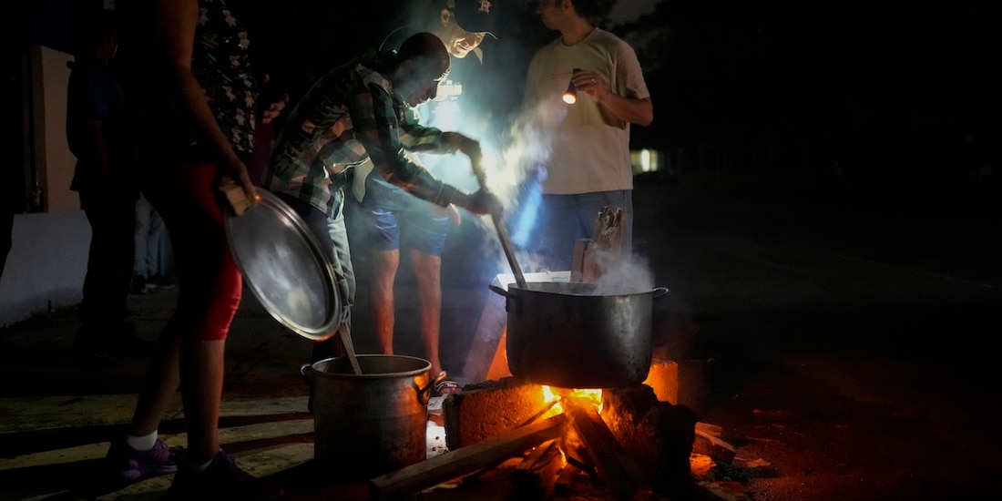 Pobladores de Cuba cocinan en la calle en la oscuridad, guiados por una fogata.