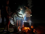 Pobladores de Cuba cocinan en la calle en la oscuridad, guiados por una fogata.