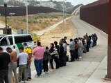 Migrantes que buscan asilo en EU hacen fila mientras esperan ser procesados después de cruzar la frontera, ayer, en San Diego, California.