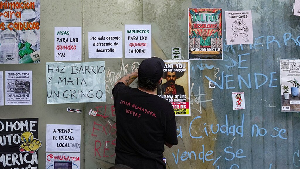 Un hombre coloca un cartel en contra de la gentrificación, el 4 de julio.