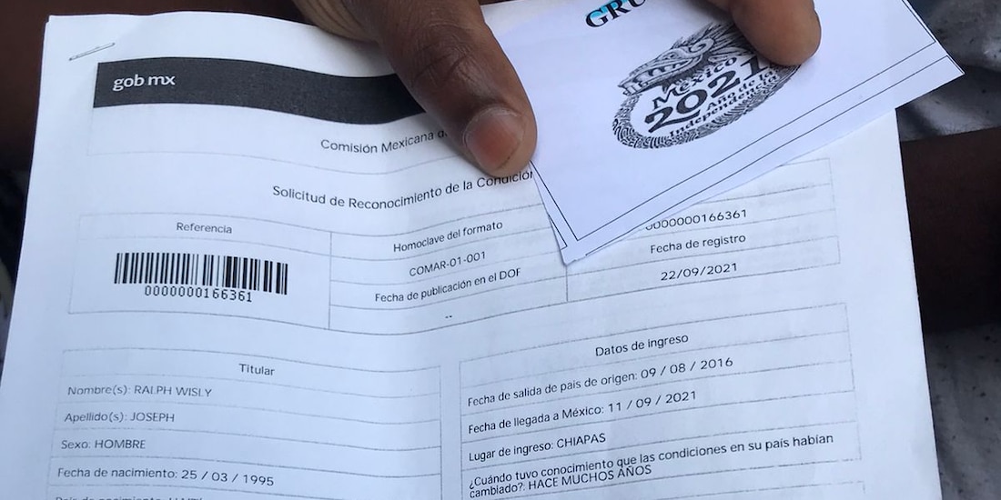 Un migrante muestra su solicitud de refugio