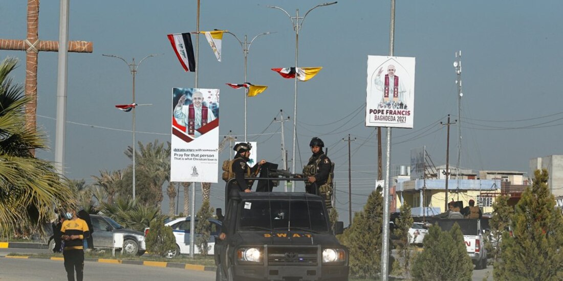 Banderas y carteles del Vaticano que anuncian la visita del Papa Francisco en una calle de Qaraqosh, Irak
