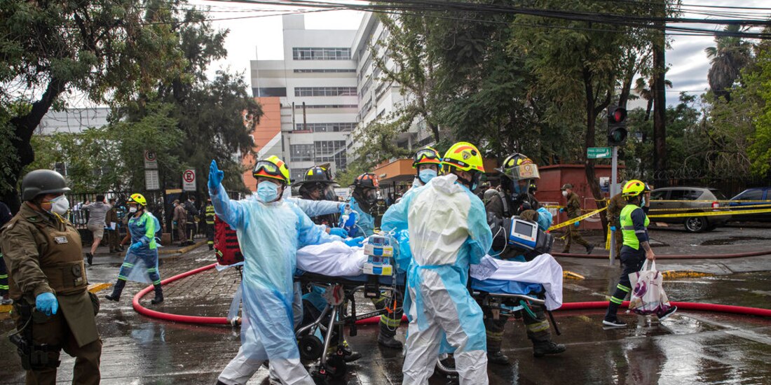 Trabajadores de salud ayudan a evacuar a un paciente con COVID-19 luego de un incendio en el hospital San Borja en Santiago de Chile.