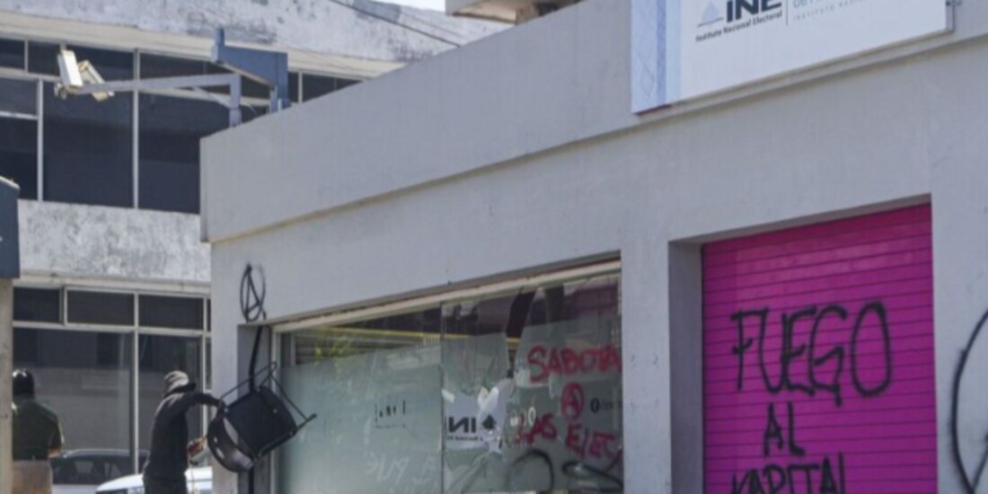 Un hombre encapuchado golpea los cristales de las instalaciones de la Junta Local Ejecutiva del INE en Xalapa, como parte de una jornada de vandalismo, ayer.
