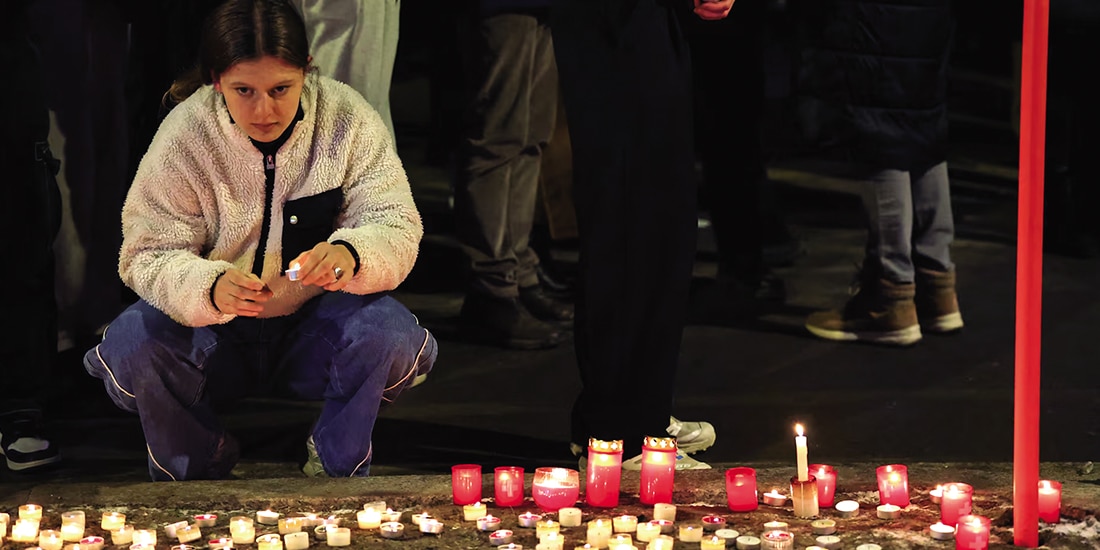 Una mujer sostiene una vela afuera del bar “Le Constellation”, después de un incendio y explosión durante una fiesta de Año Nuevo, ayer.