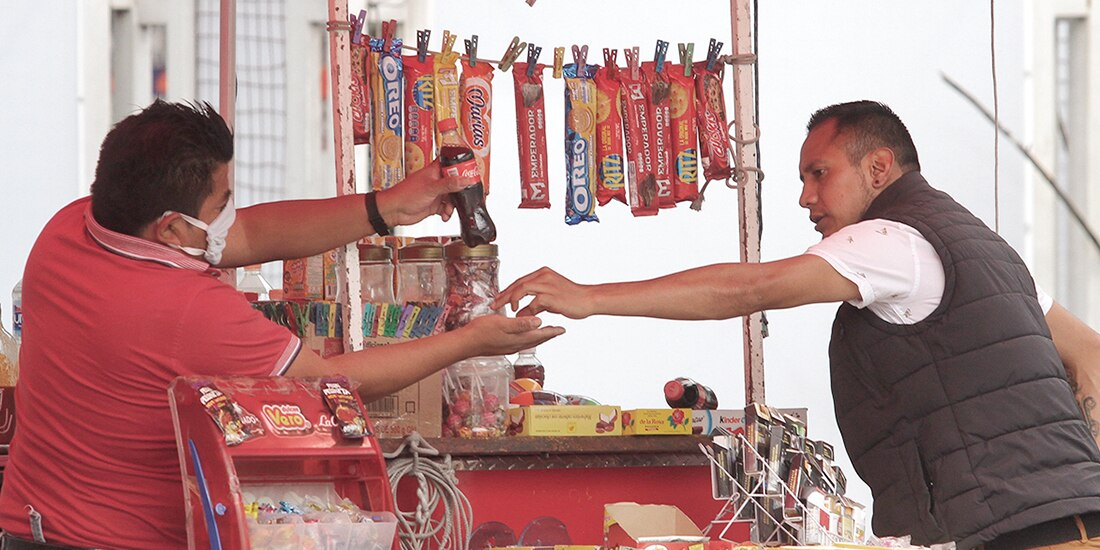 Un hombre vende un refresco a un hombre en la calle, en 2020.